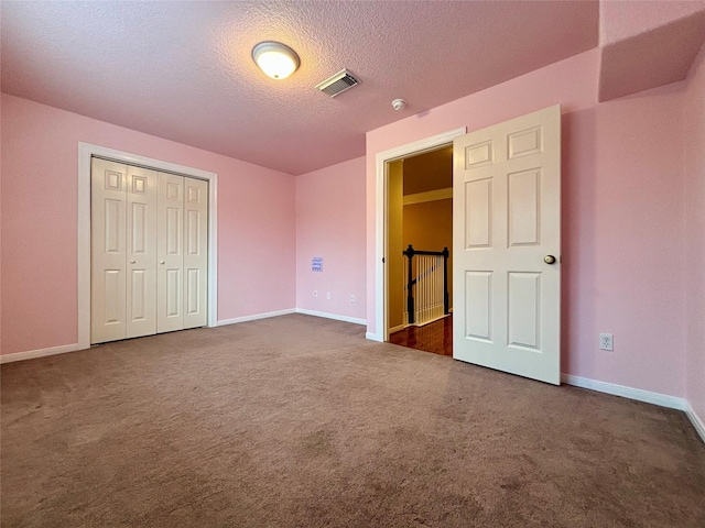 unfurnished bedroom featuring visible vents, dark carpet, and baseboards