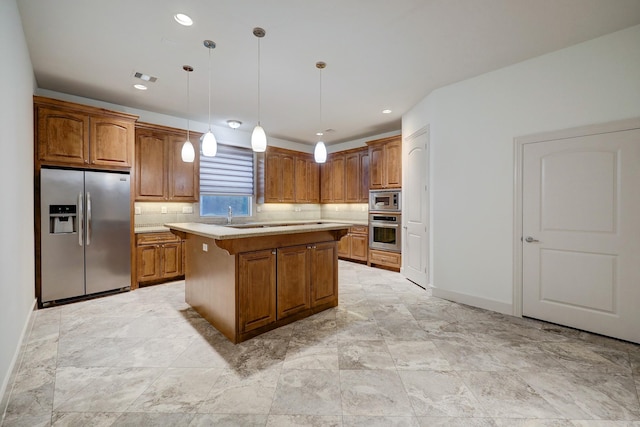 kitchen with pendant lighting, light countertops, appliances with stainless steel finishes, brown cabinetry, and a kitchen island