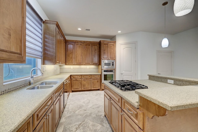 kitchen with pendant lighting, stainless steel appliances, brown cabinetry, a sink, and light stone countertops