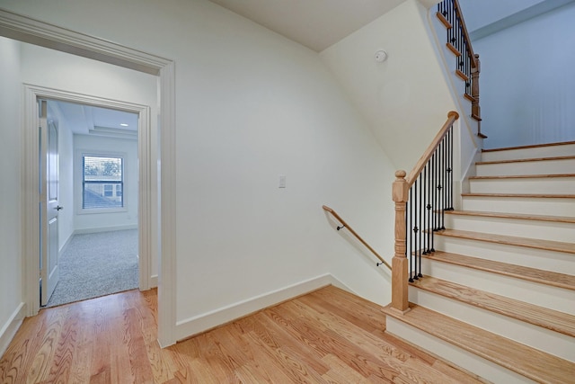 staircase featuring baseboards and wood finished floors