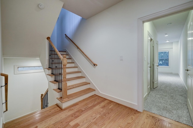 staircase featuring carpet floors, wood finished floors, and baseboards