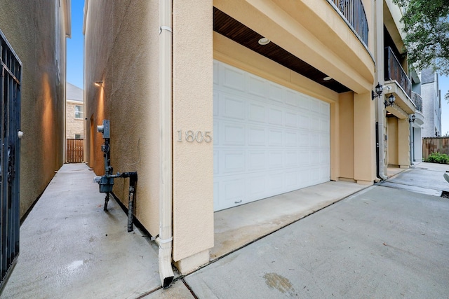 garage featuring concrete driveway and fence