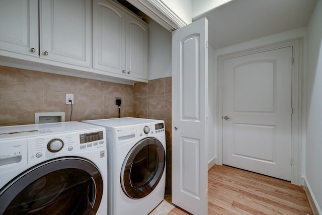 laundry room with light wood finished floors, tile walls, cabinet space, and washer and dryer