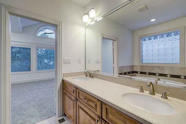 bathroom featuring double vanity, a garden tub, visible vents, and a sink