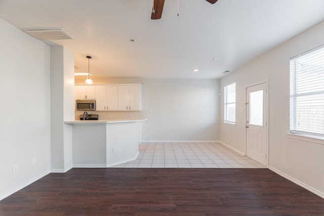 14331 Melody Glen Ln, Houston, TX 77014 - kitchen with stainless steel microwave, light wood finished floors, a ceiling fan, white cabinets, and light countertops