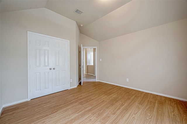 unfurnished bedroom featuring light wood-style floors, a closet, visible vents, and vaulted ceiling