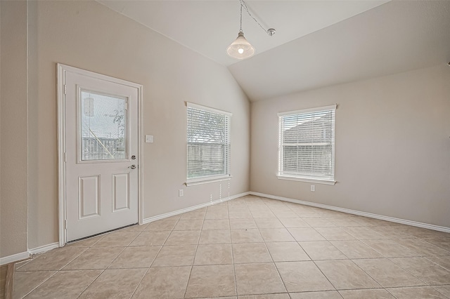 interior space with vaulted ceiling, light tile patterned flooring, and baseboards