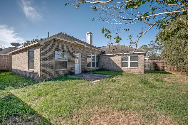 back of house featuring a yard, brick siding, and fence