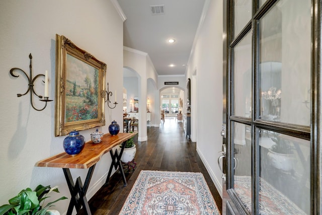 corridor with dark wood-style floors, arched walkways, visible vents, and baseboards