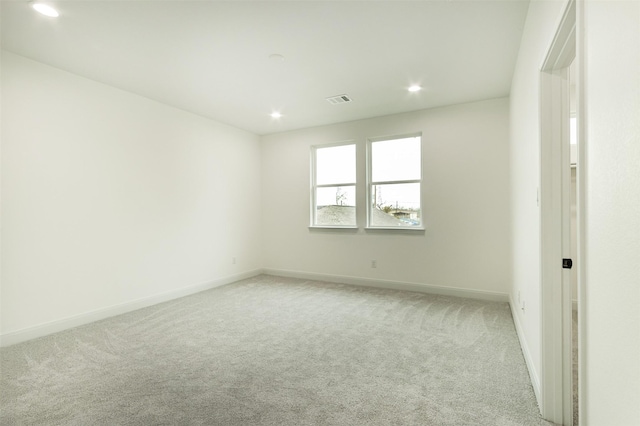 empty room featuring recessed lighting, light colored carpet, baseboards, and visible vents