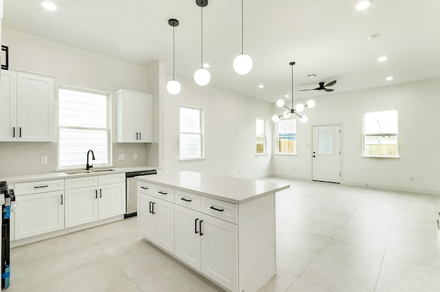 kitchen featuring a kitchen island, decorative light fixtures, light countertops, appliances with stainless steel finishes, and a sink