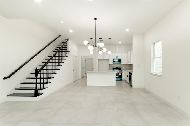 kitchen featuring dishwashing machine, a kitchen island, gas range, white cabinetry, and stainless steel microwave