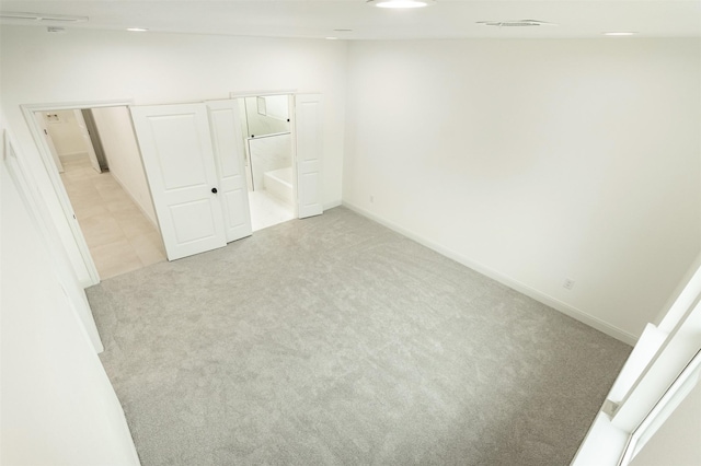 unfurnished bedroom featuring recessed lighting, baseboards, light colored carpet, and ensuite bathroom