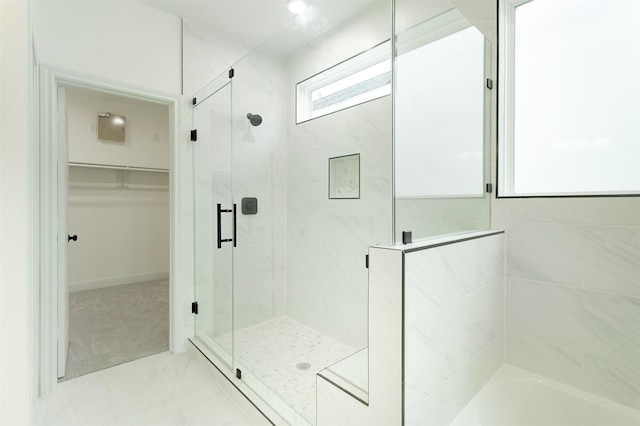 full bathroom with a bathing tub, a shower stall, and a walk in closet