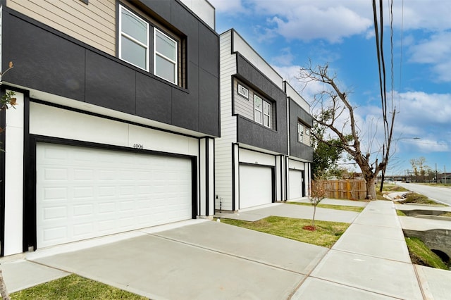 view of front of property featuring a garage, stucco siding, driveway, and fence