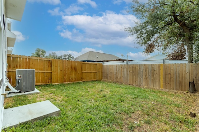 view of yard with a fenced backyard and central AC