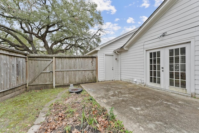 view of yard featuring a gate, fence, a patio, and french doors