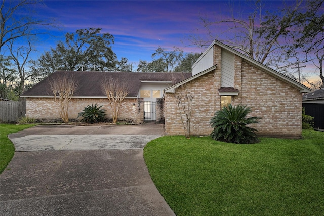 mid-century inspired home with brick siding, concrete driveway, and a front yard