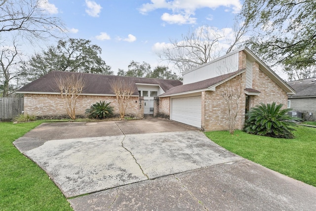 mid-century modern home featuring a garage, brick siding, fence, concrete driveway, and a front yard