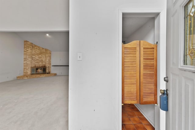 hall featuring dark tile patterned floors, dark carpet, and vaulted ceiling