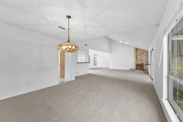 unfurnished living room with visible vents, light colored carpet, lofted ceiling, a textured ceiling, and a fireplace