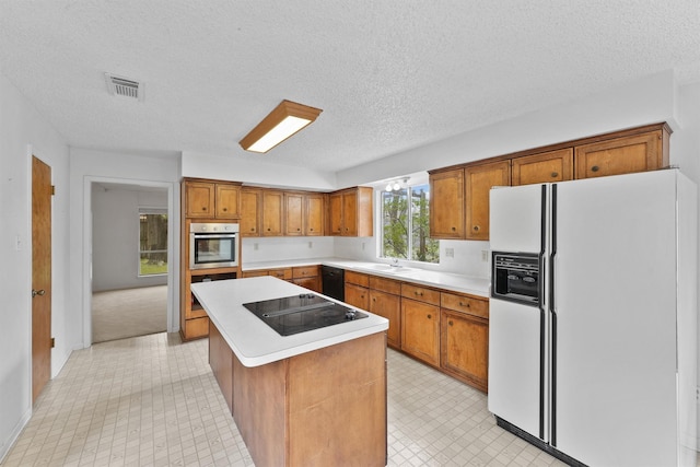 kitchen with black appliances, a kitchen island, light countertops, and brown cabinetry