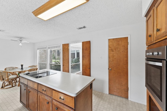 kitchen with visible vents, brown cabinetry, oven, black electric stovetop, and light countertops