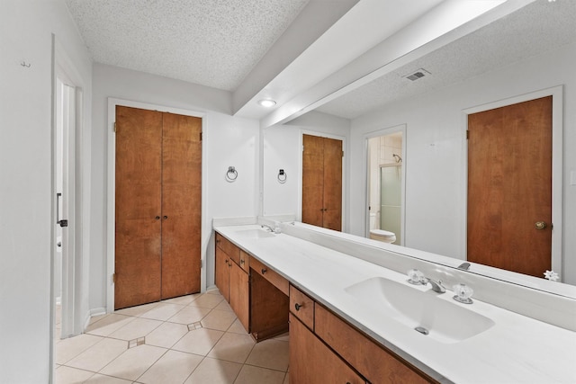 bathroom with double vanity, visible vents, toilet, a sink, and a textured ceiling