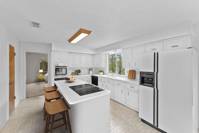 kitchen with white cabinets, light floors, a center island, light countertops, and black appliances