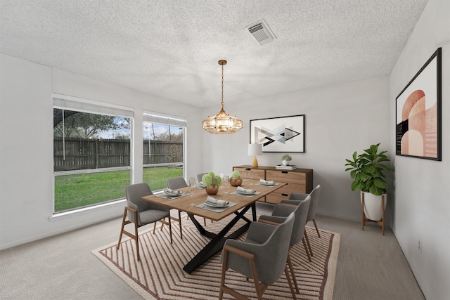 carpeted dining area featuring a chandelier, a textured ceiling, and visible vents