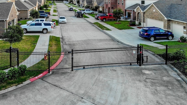 view of road featuring a residential view, a gate, and curbs