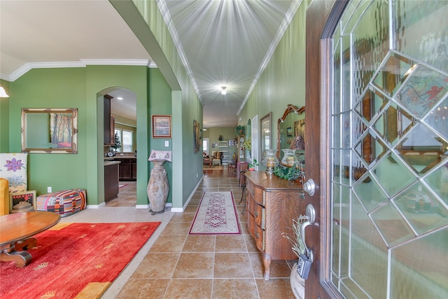 entrance foyer with arched walkways, crown molding, baseboards, and tile patterned floors