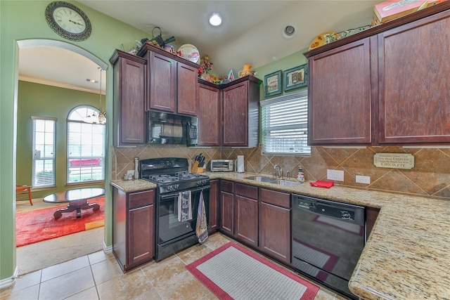 kitchen featuring arched walkways, decorative backsplash, light stone countertops, black appliances, and a sink