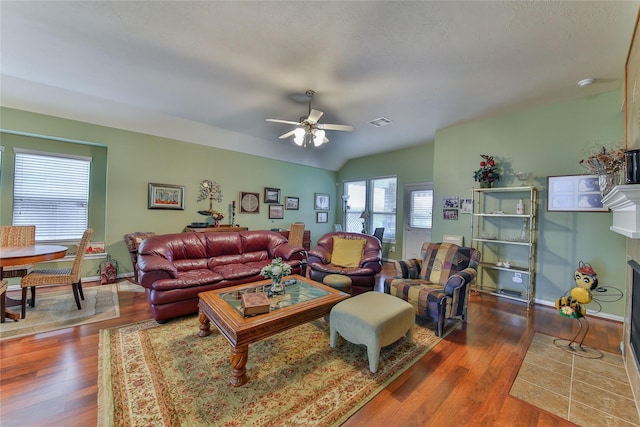 living room with visible vents, a fireplace with flush hearth, a ceiling fan, wood finished floors, and baseboards