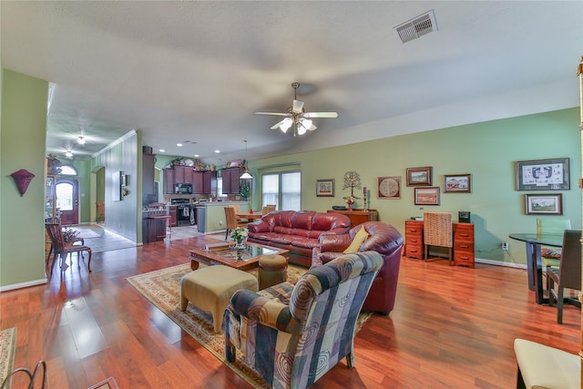 living area with ceiling fan, dark wood-type flooring, visible vents, and baseboards