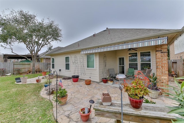 back of property featuring a lawn, a patio, roof with shingles, fence, and brick siding