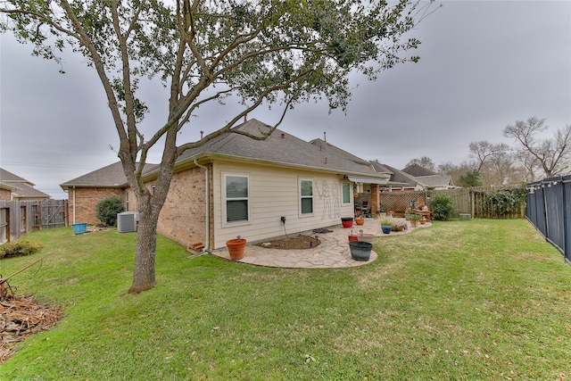 rear view of house featuring a yard, a patio, brick siding, and a fenced backyard