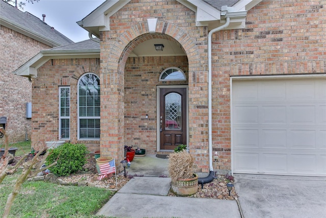 entrance to property with brick siding, an attached garage, and roof with shingles