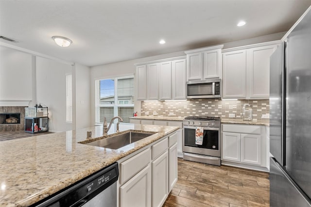 kitchen with visible vents, appliances with stainless steel finishes, light stone counters, white cabinetry, and a sink