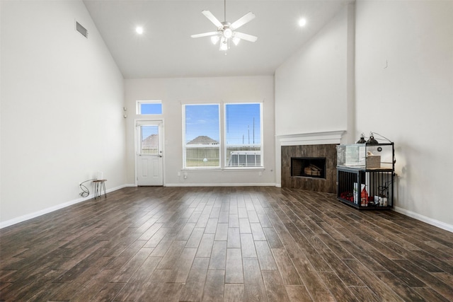 unfurnished living room featuring ceiling fan, high vaulted ceiling, dark wood-style flooring, a fireplace, and visible vents