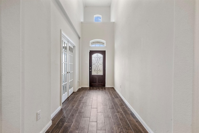 foyer with a high ceiling, baseboards, and wood finish floors