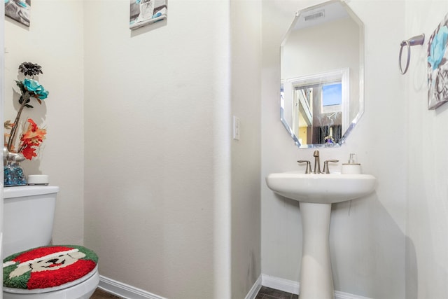 half bath with baseboards, visible vents, and toilet