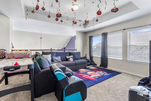 carpeted living room featuring baseboards and a tray ceiling