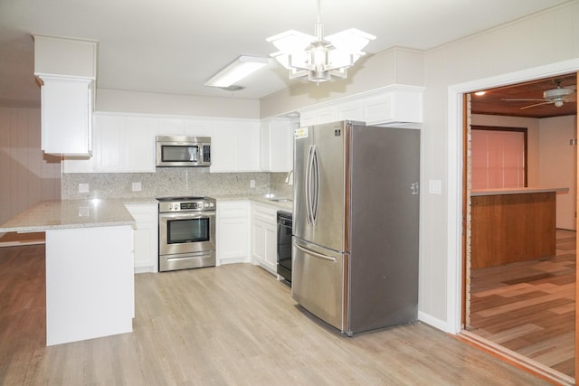 kitchen with decorative backsplash, appliances with stainless steel finishes, a peninsula, light wood-style floors, and white cabinetry