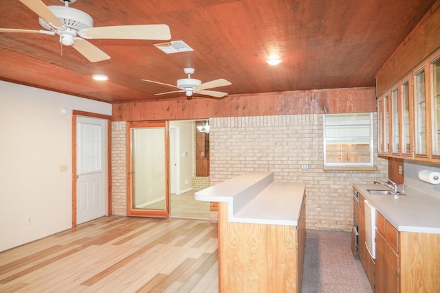 kitchen featuring wood ceiling, brick wall, glass insert cabinets, light countertops, and a sink