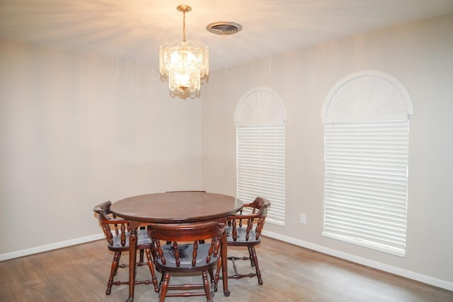 dining area with a chandelier, visible vents, baseboards, and wood finished floors