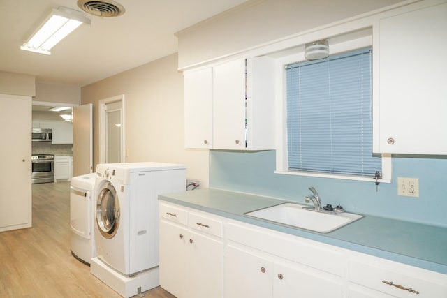 laundry room with cabinet space, visible vents, washer and dryer, light wood-type flooring, and a sink