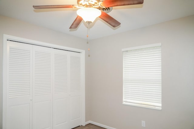 unfurnished bedroom with ceiling fan, a closet, and baseboards