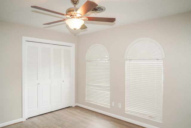 unfurnished bedroom with baseboards, visible vents, ceiling fan, light wood-style floors, and a closet