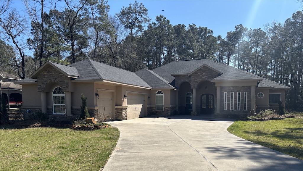 ranch-style home featuring a garage, a front lawn, and stucco siding